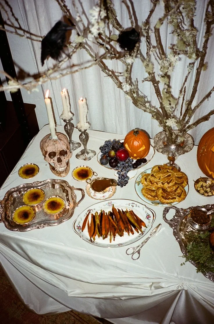 A table set for a spooky Halloween Feast featuring festive decorations and themed dishes.
