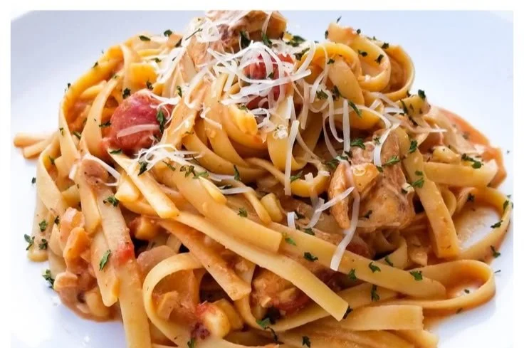 Bowl of creamy Chipotle chicken pasta topped with fresh herbs and spices.