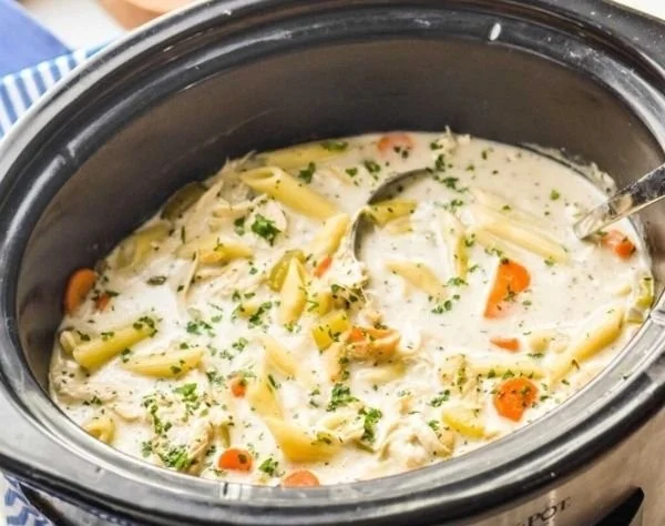 Creamy crockpot chicken noodle soup served in a bowl with herbs