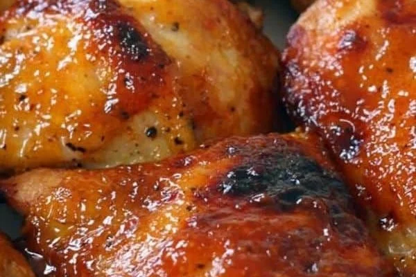 Crispy oven baked BBQ chicken served on a plate with fresh herbs.