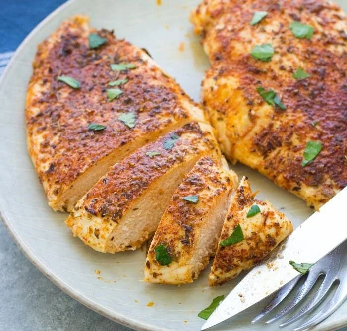 Juicy easy baked chicken breasts served on a plate with herbs and spices