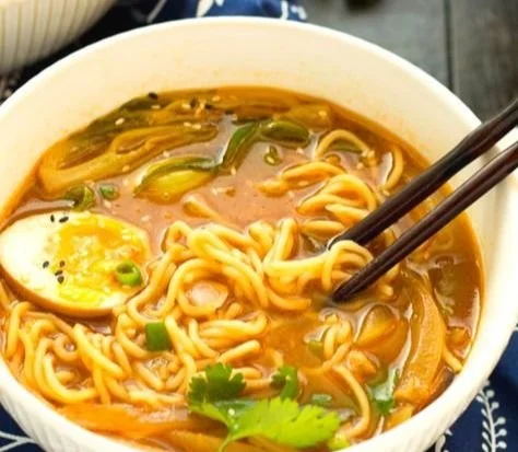 A bowl of easy chicken ramen topped with green onions and egg.