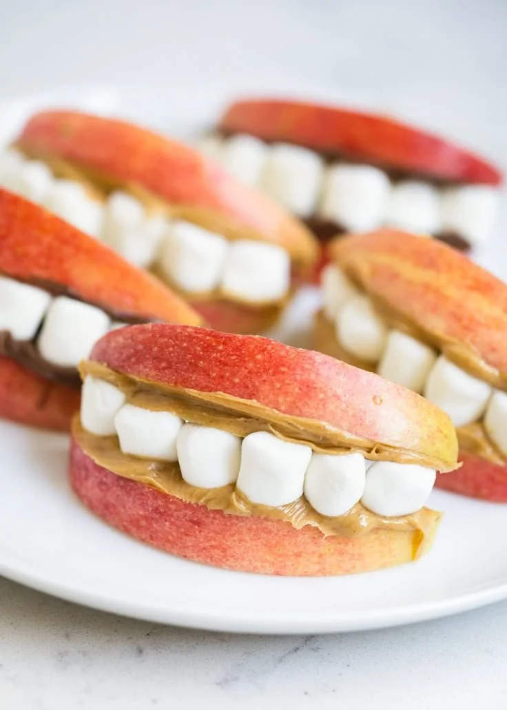 A variety of healthy Halloween snacks including fruit and veggie treats.