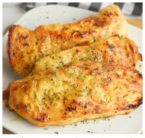 Oven-baked honey mustard chicken garnished with herbs on a white plate