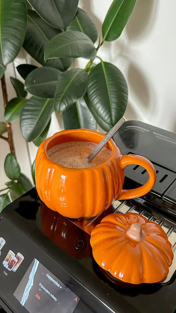 Delicious pumpkin spice latte in a pumpkin mug surrounded by fall decor